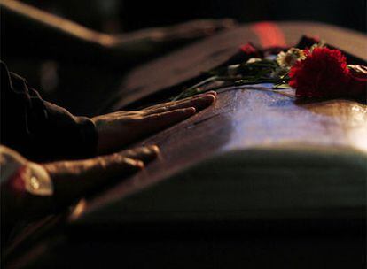 Ciudadanos que acudieron al funeral de Víctor Jara tocan el ataúd del cantautor ayer en Santiago.