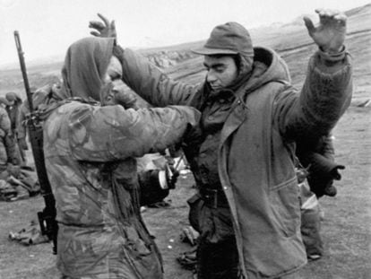 A British soldier checks on an Argentine prisoner after the surrender of the Argentine armed forces, on June 15, 1982. 