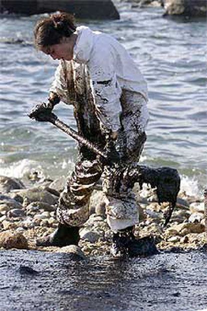 Una voluntaria recoge fuel ayer en la playa de Muxía.