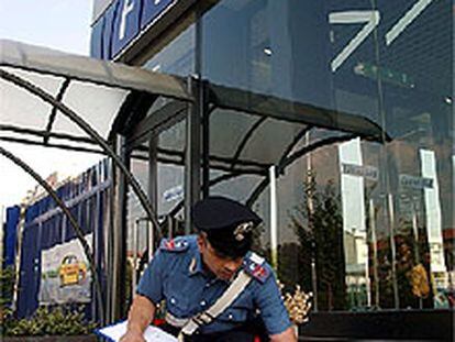 Un <i>carabinieri</i> recoge pruebas del artefacto explosivo colocado junto al concesionario de Fiat