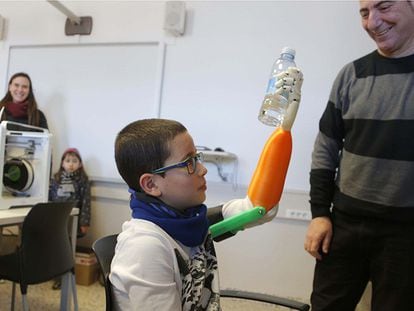 El niño Unai Blanco agarra un botellín de agua con su mano artificial realizada con una impresora 3D.