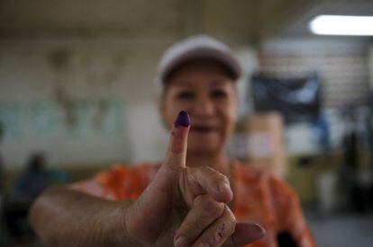 Una mujer muestra su dedo manchado de tinta después de emitir su voto.