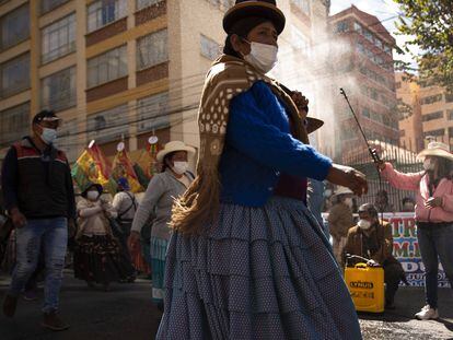 Una mujer rocía desinfectante a manifestantes en medio de la pandemia COVID-19, durante una marcha pidiendo acceso gratuito a internet y computadoras al gobierno, para que sus hijos puedan tomar clases en línea, en La Paz, Bolivia.