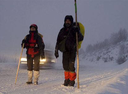 Dos peregrinos caminan por una carretera, nevada, de Lugo.
