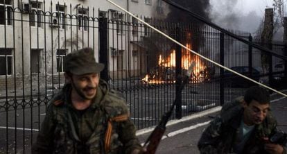 Separatistas prorrusos se alejan de un carro ardiendo en Donestk.