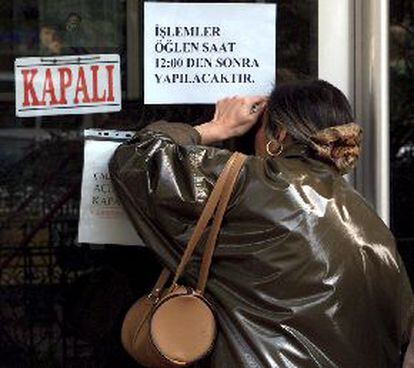 Una mujer turca mira a través de la puerta de una oficina de cambio de moneda cerrada, ayer en Estambul.