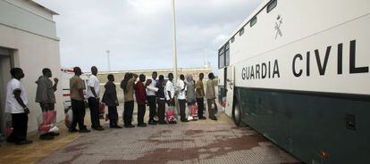 Un grupo de inmigrantes subsaharianos hace cola para subir a un autob&uacute;s de la Guardia Civil en Tarifa para ser trasladado a C&aacute;diz.