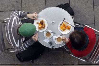 Una pareja desayuna con café y tostadas en la terraza de un café de Madrid.