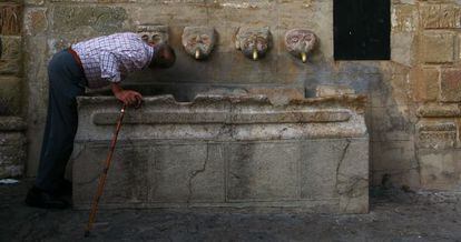 Un vecino de Grazalema bebe de una fuente p&uacute;blica.