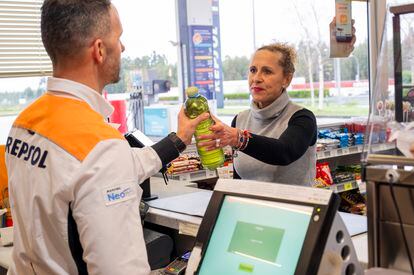 Una mujer entrega una botella de aceite de cocina usado en una estación de servicio de Repsol en Galicia. /REPSOL