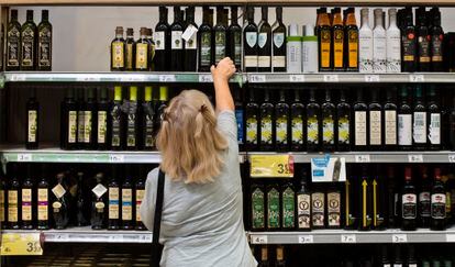 Una clienta de un supermercado español elige una botella de aceite de oliva.