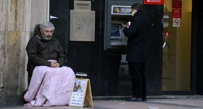 Un mendigo junto a un cajero en Madrid, en 2013.