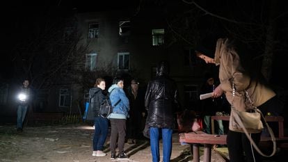 Varias personas observaban un edificio de apartamentos de tres plantas dañado tras un ataque ruso con drones el 4 de abril de 2024 en Járkov.