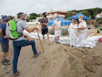 Cuatro personas voluntarias responden las dudas de dos excursionistas junto al nido de tortuga boba en Marbella.