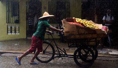 Un vendedor de mango con su puesto ambulante va a resguardarse ante las lluvias durante la tormenta Isaias, en Santo Domingo.
