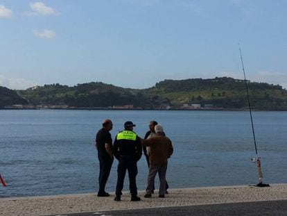 Pescadores comentan la jornada con un policía junto al Tajo, en Lisboa.