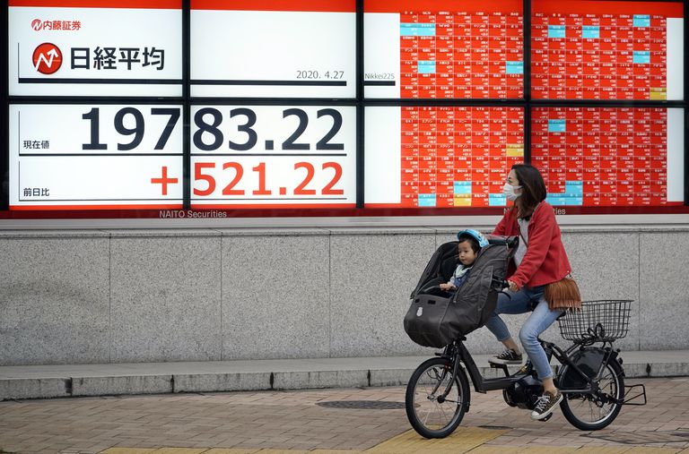 Una mujer y un niño frente a un indicador de la Bolsa de Japón, el lunes en Tokio.