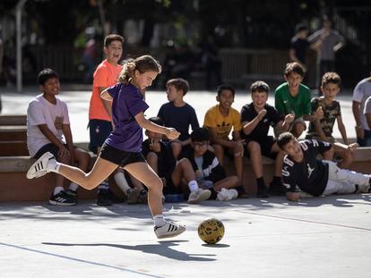 Rita, alumna de 1º de ESO del instituto Pau Claris de Barcelona, juega al futbol, animada por los chicos, durante el recreo.