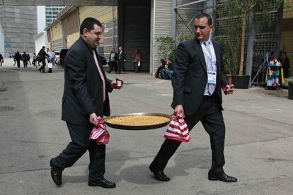 Dos personas sacan una paella recién elaborada del pabellón multiproducto, durante la tercera jornada del salón Alimentaria.