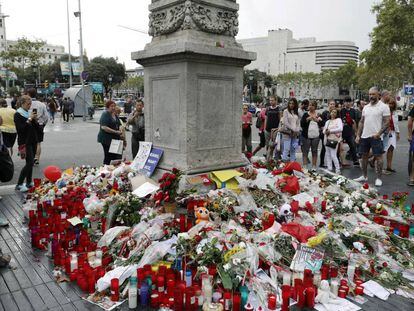 Barceloneses y turistas hacen un alto en el Memorial con flores a las víctimas del atentado terrorista, situado al comienzo de las Ramblas de Barcelona.