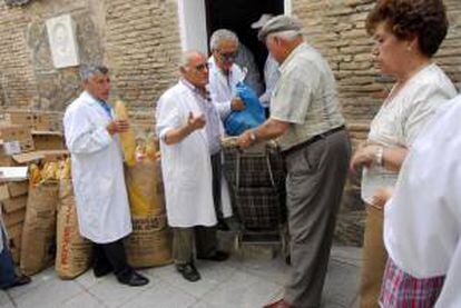 Cipriano González (2i), popularmente conocido como "el amigo de los pobres", durante su tradicional reparto de comida, organizado hoy por El Socorro de los Pobres de la ciudad e Toledo.