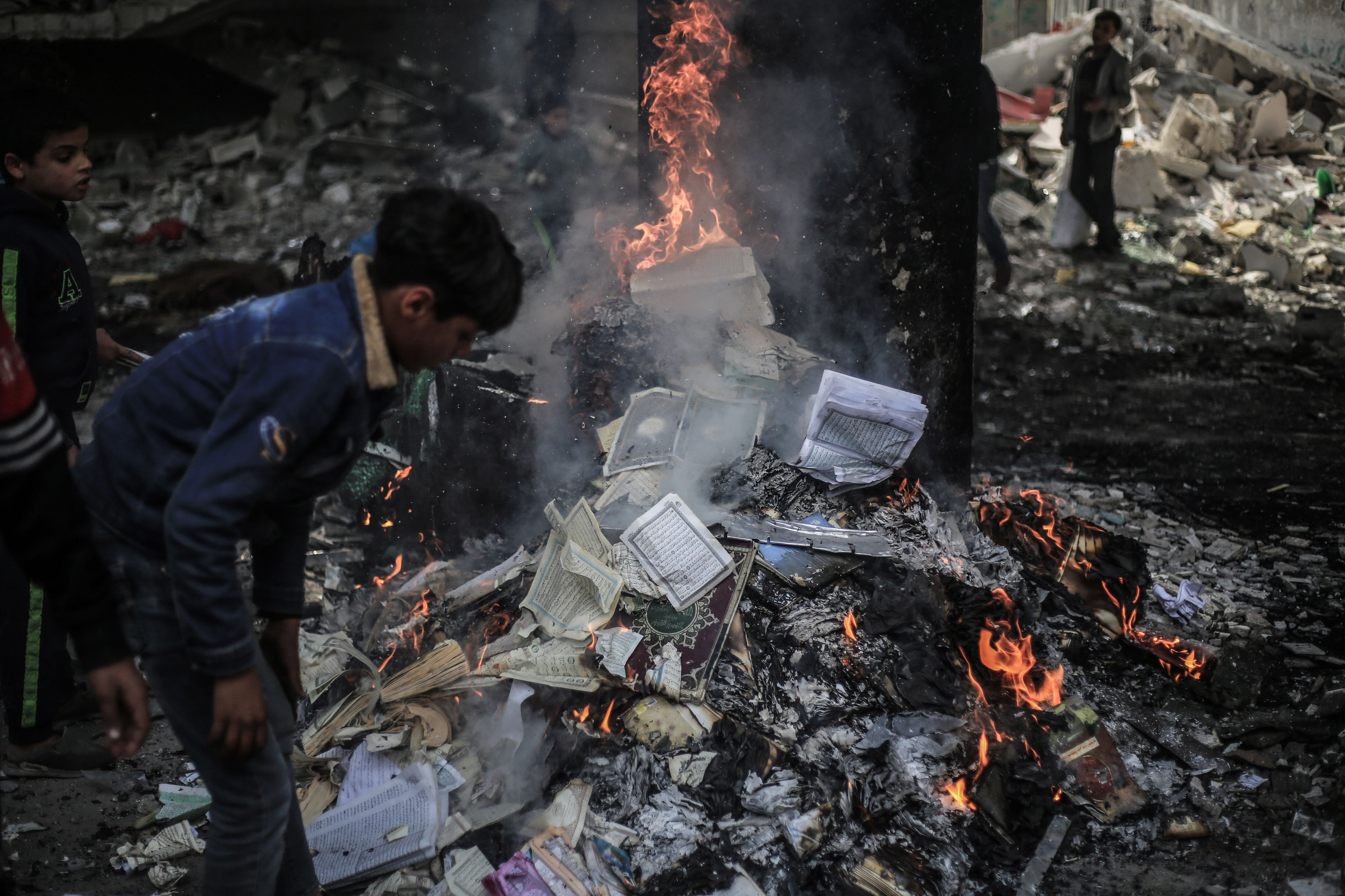 Ejemplares del Corán arden en las ruinas de la mezquita de Al Huda, tras el bombardeo israelí de este lunes. 