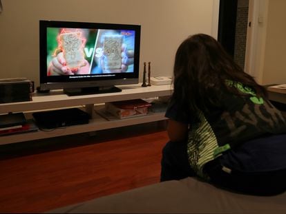 Un niño ve en la televisión en su casa publicidad de alimentos poco saludables.