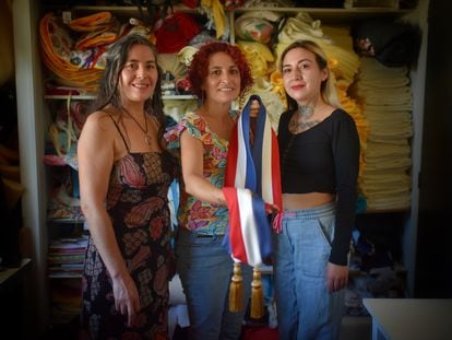 Ingrid Albornoz (izquierda), Marta Gatica y Arety Alvarado, integrantes del Sindicato Revolucionario Textil, muestran la banda que han confeccionado para el presidente Gabriel Boric, el 9 de marzo de 2022 en Santiago de Chile.