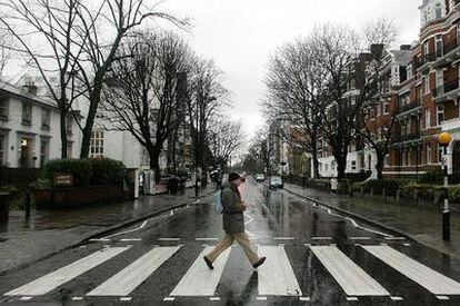 Un viandante cruza por el famoso paso de cebra de Abbey Road que fue la carátula del disco de The Beatles del mismo nombre.