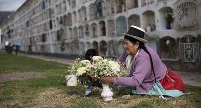 Una mujer adorna con flores la tumba de un familiar.