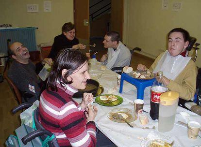 Charo Yago, al fondo de la imagen, da de comer a uno de los discapacitados de un centro madrileño.