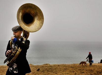 Un músico sopla la tuba  en la playa de San Sebastián de la Barceloneta.