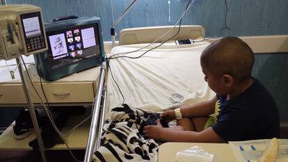 Un niño internado en una sala de oncología juega un videojuego en una consola de La Guardia.