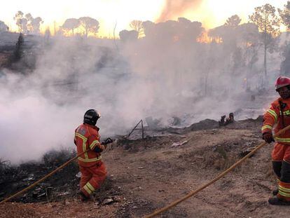 Los bomberos sofocan las llamas en el incendio de este domingo en el asentamiento chabolista de San Jorge, en Palos de la Frontera (Huelva).