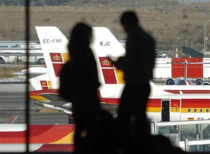 Dos pasajeros observan algunos aviones de Iberia aparcados en el aeropuerto de Barajas (Madrid).