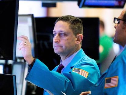 Varios trabajadores de la Bolsa contemplan los indicadores de mercado en una pantalla en Nueva York (Estados Unidos).