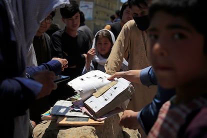 Varios afganos muestran algunas de los cuadernos y libros de las víctimas del atentado junto a un colegio de Kabul, el domingo.