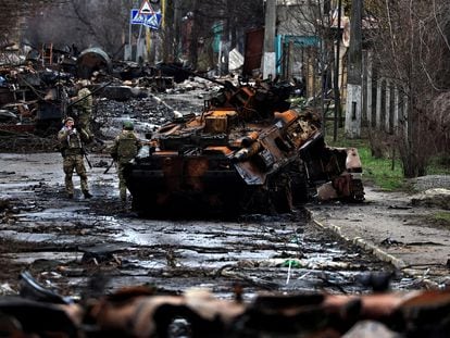 Soldados ucranios junto a un carro ruso destruido en la localidad de Bucha.