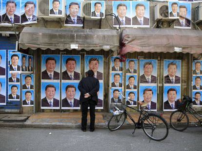 Un hombre mira un muro lleno de carteles del presidente Xi Jinping en Shangh&aacute;i