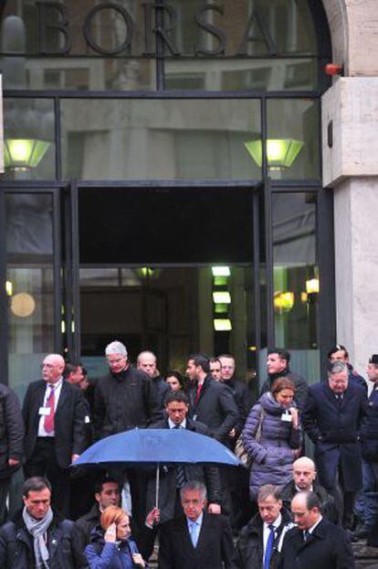 Monti, resguardado por un paraguas, sale de la Bolsa de Milán.