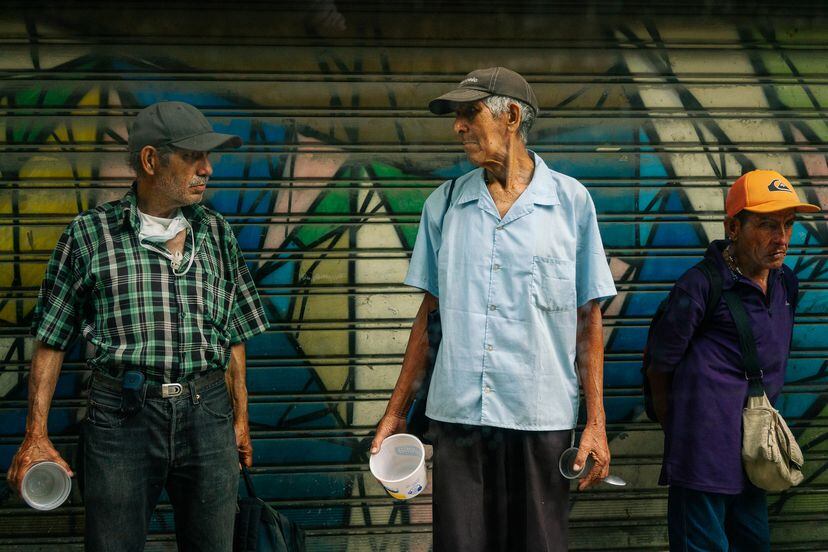 Dos hombres esperan una ración de comida que reparte la organización Puentes de Paz, en Venezuela.