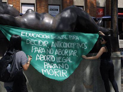 Dos mujeres protestan a favor del aborto en una escultura del artista Fernando Botero, en Medellín (Colombia).