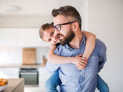 Un padre lleva a hombros a su hija en casa.