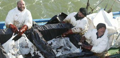 Unos pescadores recogen chapapote.
