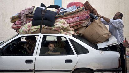 Un hombre coloca sus pertenencias en el techo de su coche con el que él y su familia regresaran a su casa, después de haber permanecido refugiados en una escuela de la ONU en Gaza.