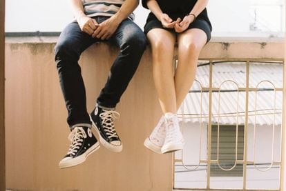 Dos adolescentes se sientan en una cornisa. 