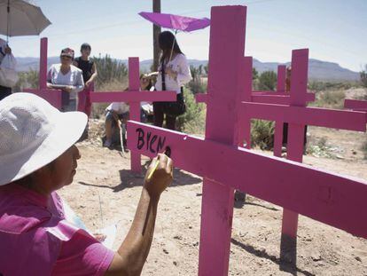 Una madre pinta en una cruz el nombre de una v&iacute;ctima de feminicidio.