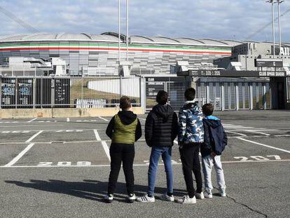 Cuatro jóvenes observan el Allianz Stadium tras la cancelación de varios partidos de la Serie A por el virus, en Turín, Italia.