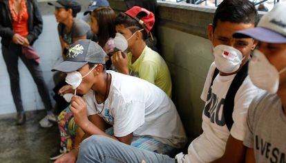 Gente con mascarillas cerca de una parada de metro en Caracas.