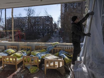 Un hombre retira las cortinas de un colegio dañado por los bombardeos en Kiev.
